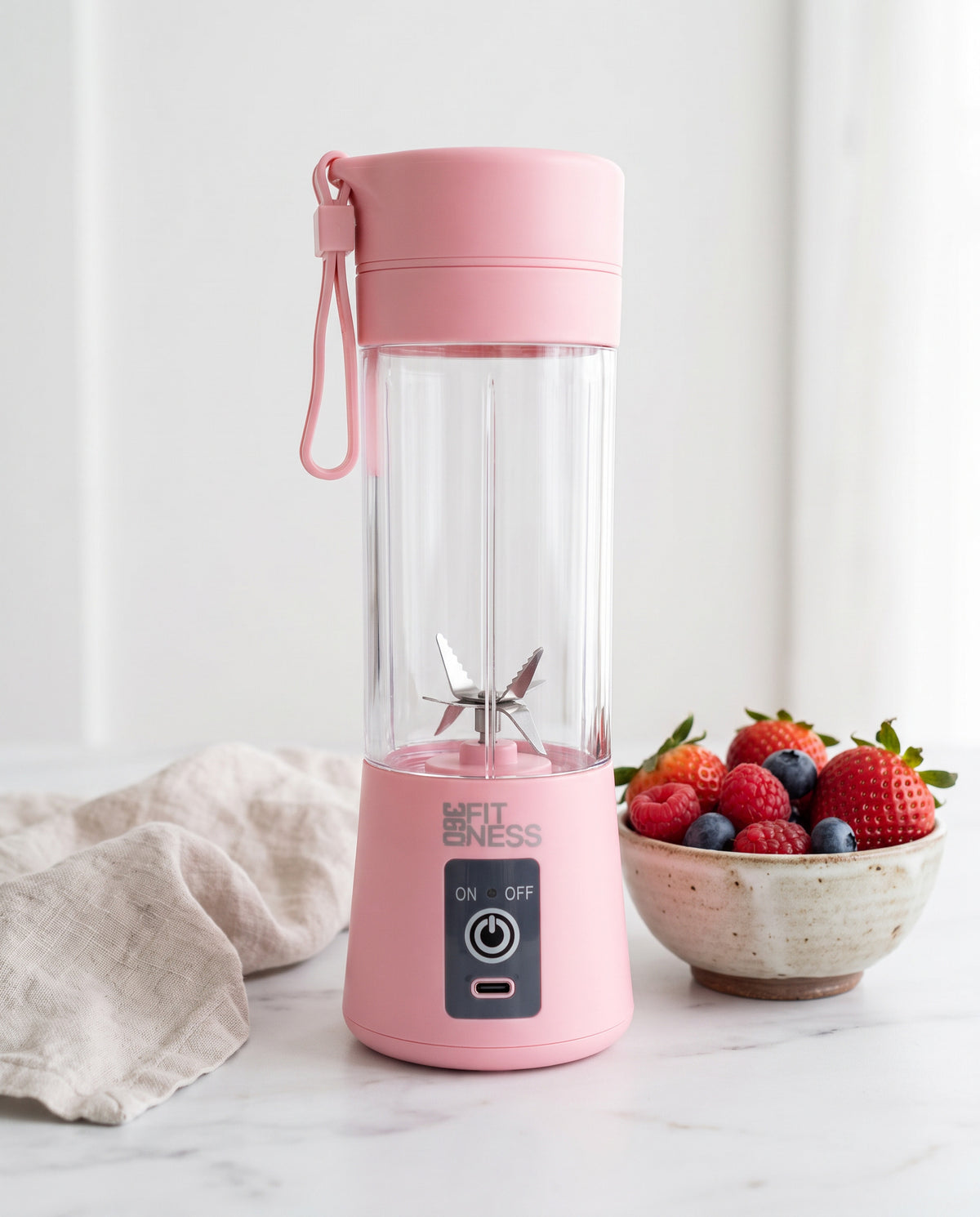360° Tragbarer Mixer PRO in Pink auf einer Marmorplatte, daneben eine Schale mit frischen Beeren